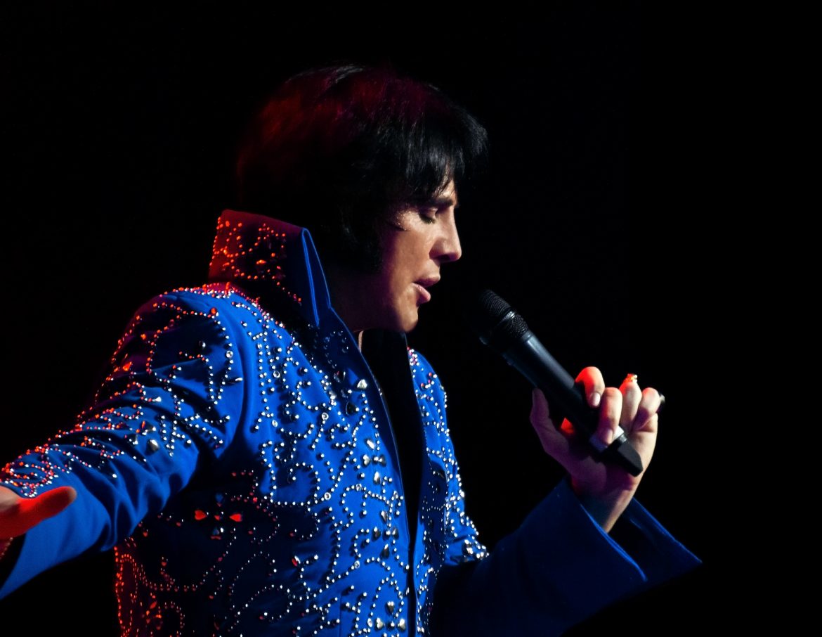 Shawn Klush singing into a mic wearing a bejewelled blue suit